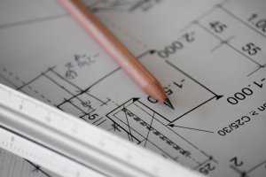 Nahaufnahme eines Bleistifts, der auf Architekturplänen liegt, mit einem Lineal in der Nähe, das technische Zeichnungen und Messungen zeigt.