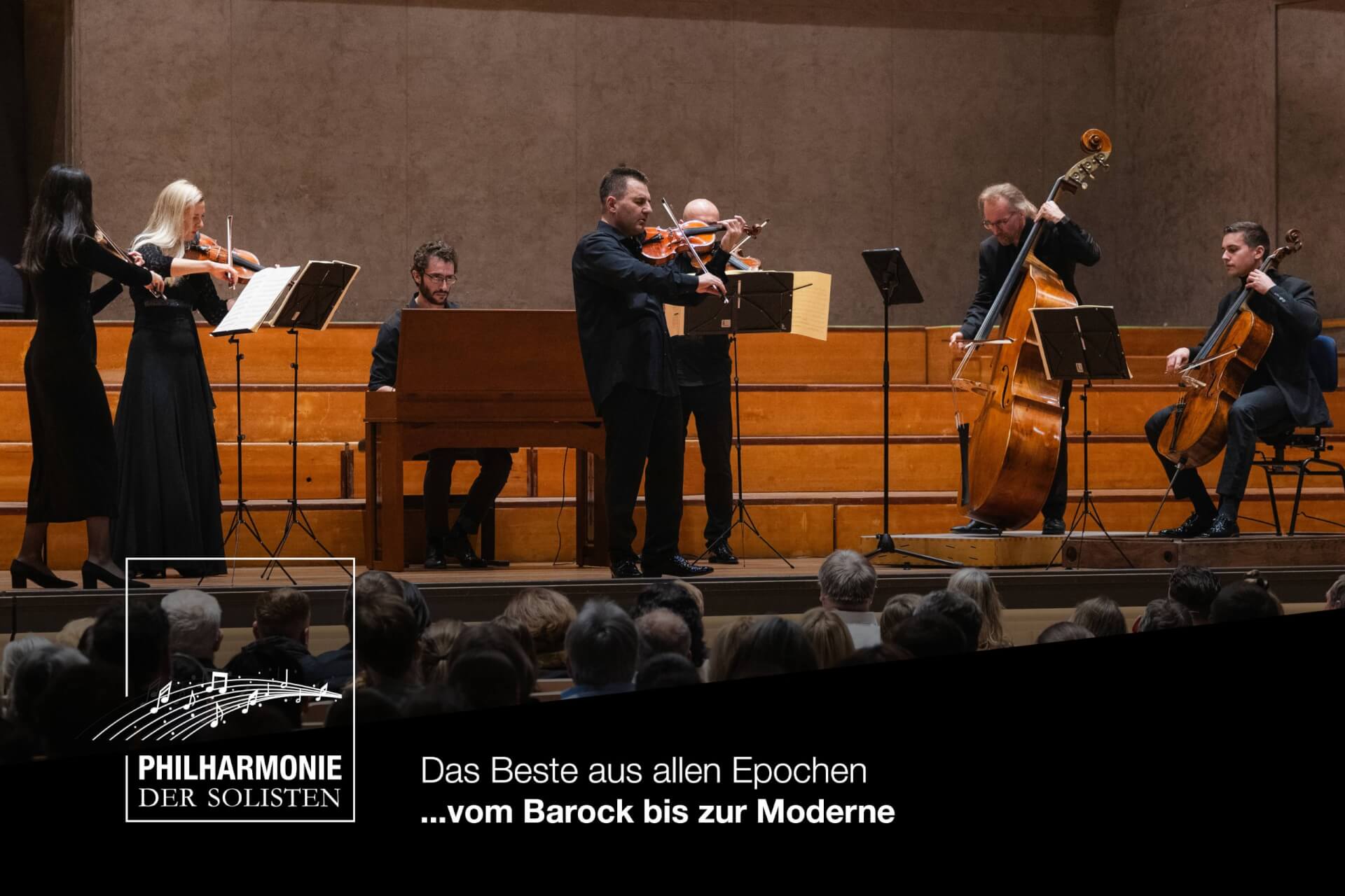 Ein Kammermusikensemble tritt vor Publikum mit Streichinstrumenten und einem Cembalo auf der Bühne auf. Auf einem Banner darunter steht: „Philharmonie der Solisten – vom Barock bis zur Moderne“.